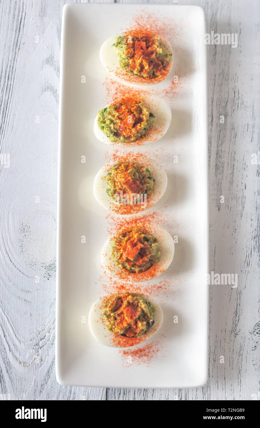 Guacamole and bacon deviled eggs on the white plate Stock Photo