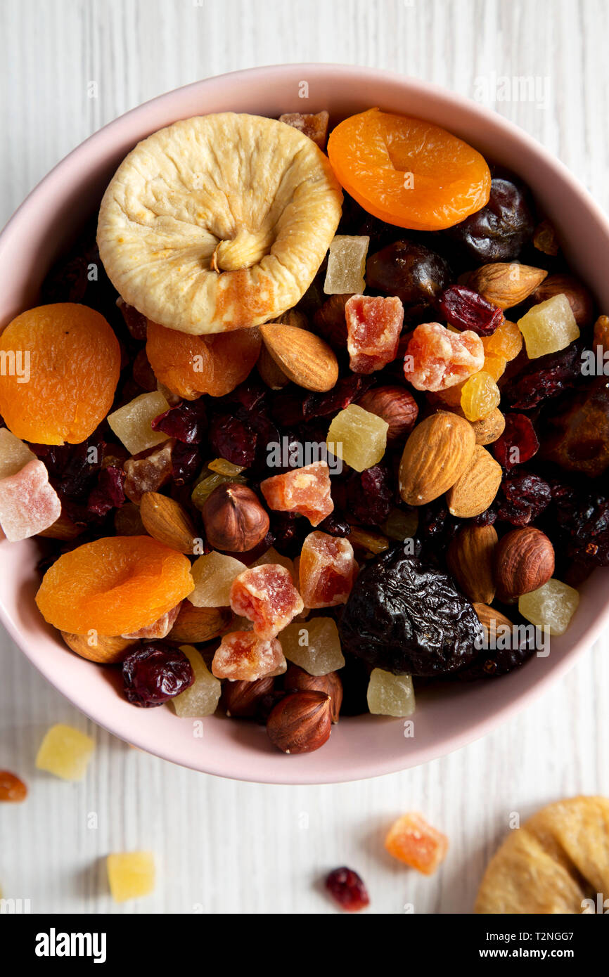 Dried fruits and nut mix in a pink bowl over white wooden surface top