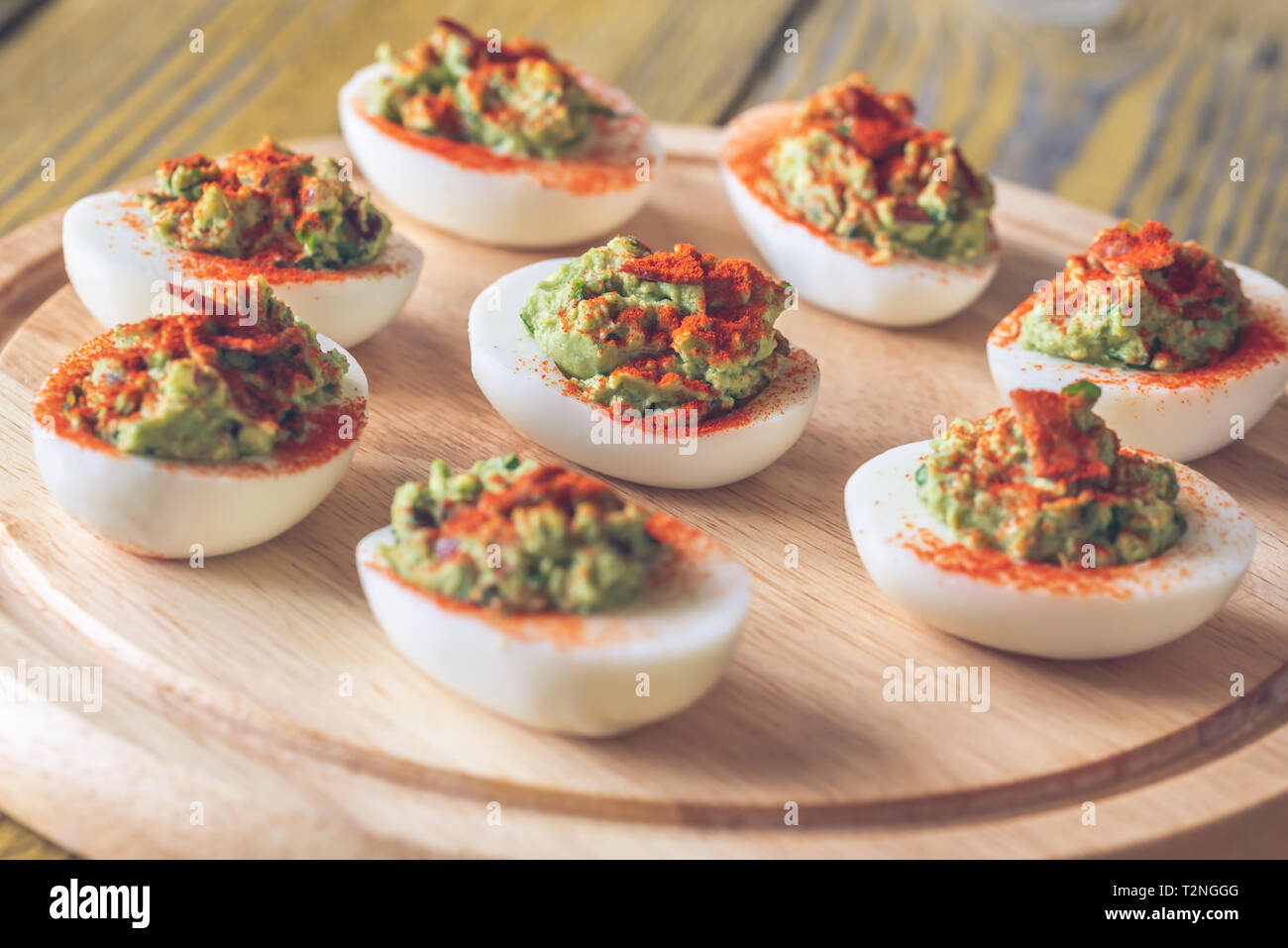 Guacamole and bacon deviled eggs on cutting board Stock Photo
