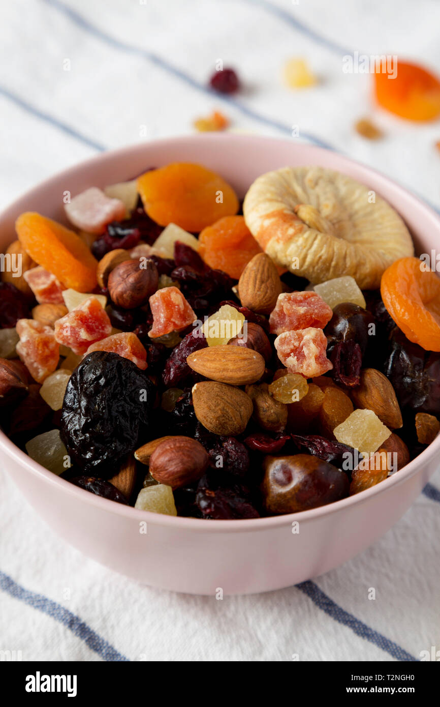 Dried fruits and nut mix in a pink bowl, side view. Closeup Stock