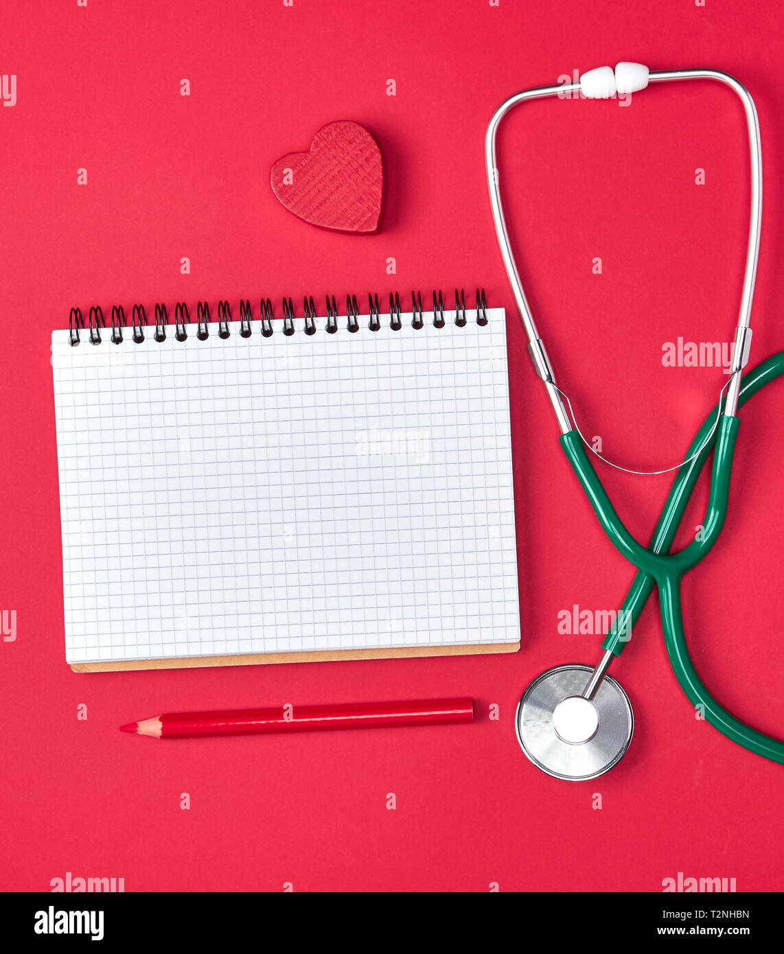open blank notepad and green medical stethoscope on red background ...