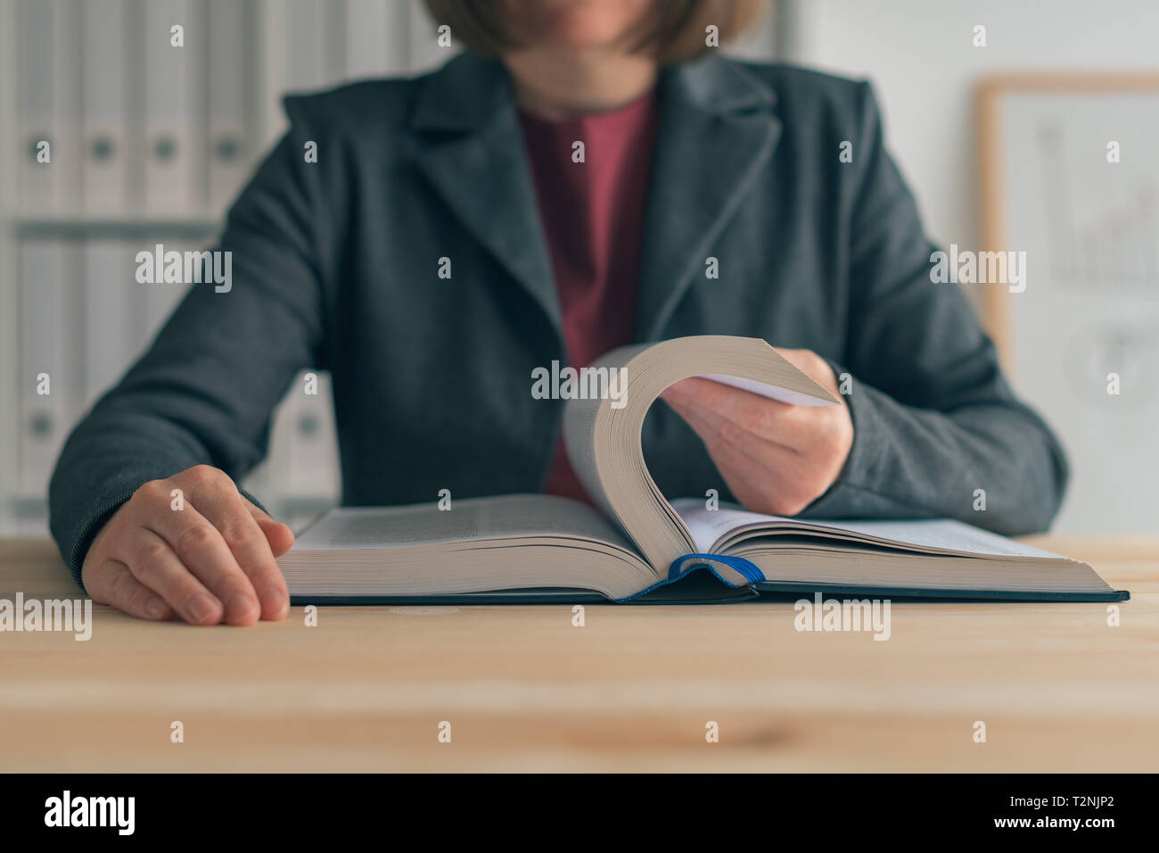Businesswoman reading book at office desk, searching for the business realted information Stock Photo