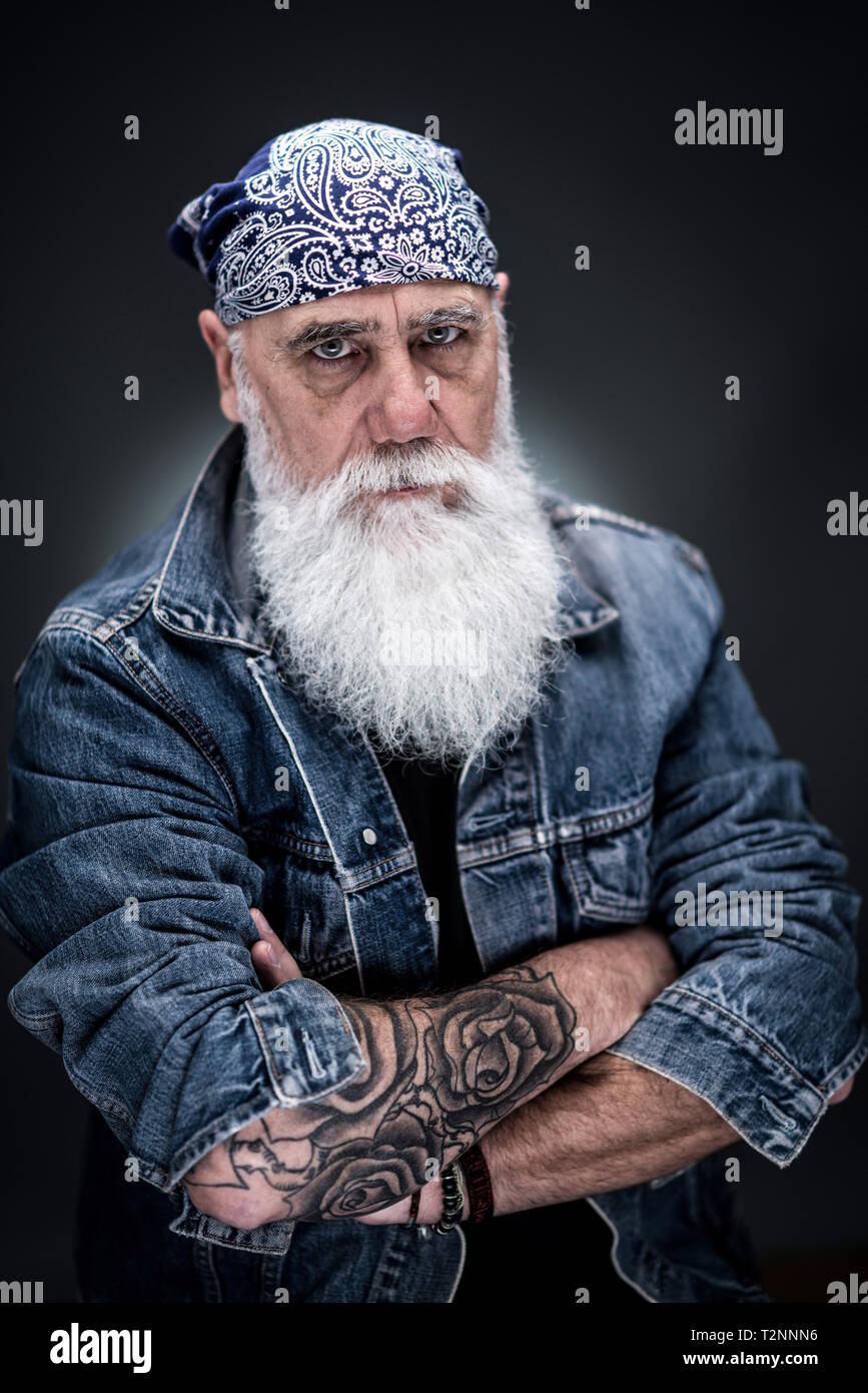 Studio Portrait Of A Senior Hipster With Tattooed Arms Wearing A