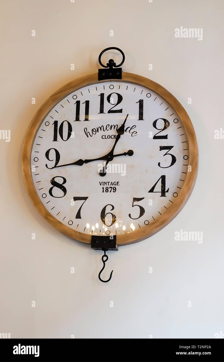 vintage wall clock on a white wall with side window light Stock Photo