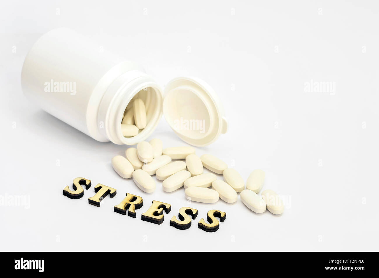 White oval pills spilled out of a white bottle on a white background