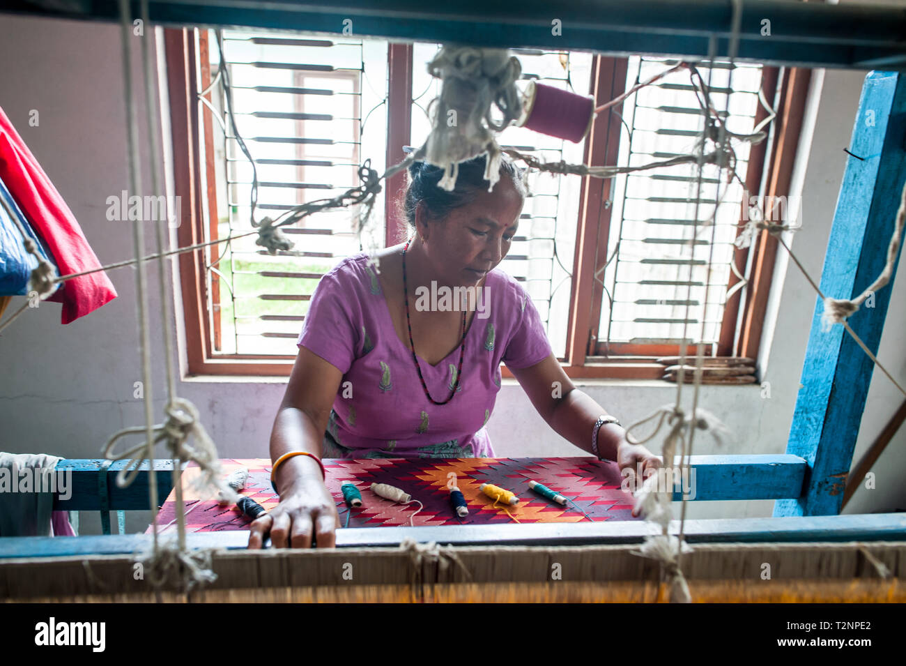 A Nepali woman embroidering silk and pashmina wool shawls by loom, at W.F. Nepal, an NGO employing marginalised women on a equal rights basis. Stock Photo