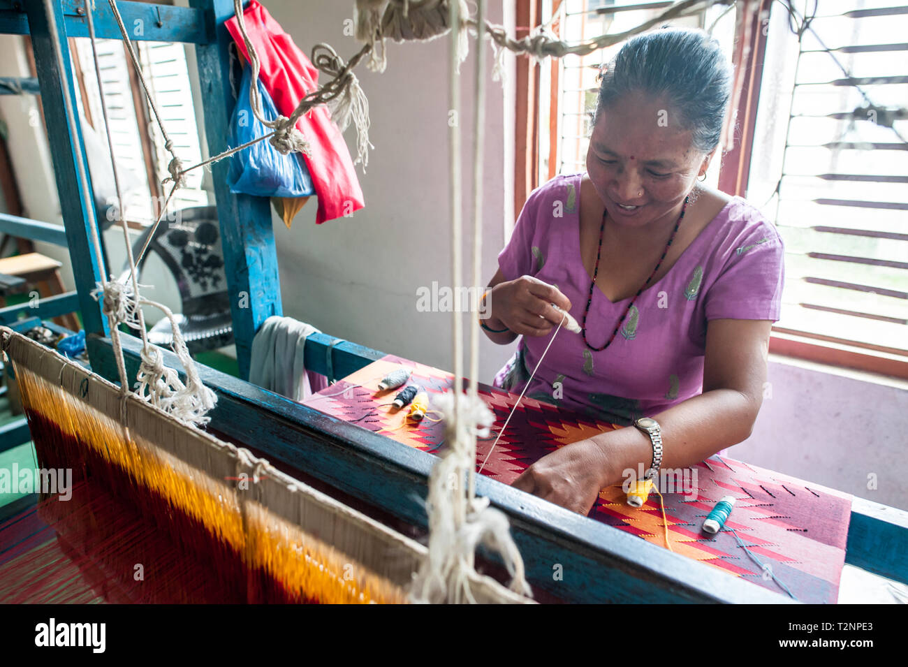 A Nepali woman embroidering silk and pashmina wool shawls by loom, at W.F. Nepal, an NGO employing marginalised women on a equal rights basis. Stock Photo