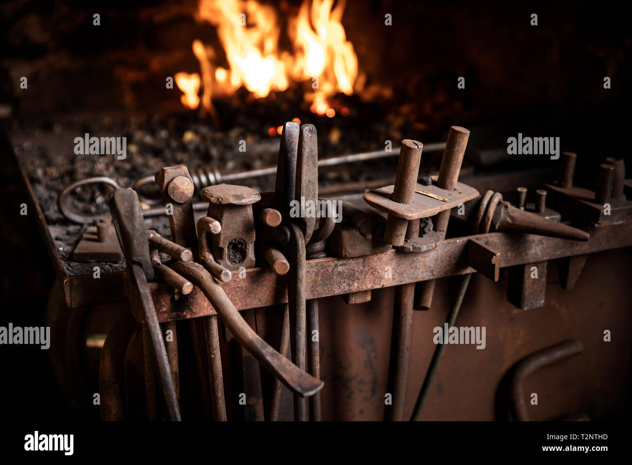 Row of tools in front of fire in blacksmiths workshop Stock Photo