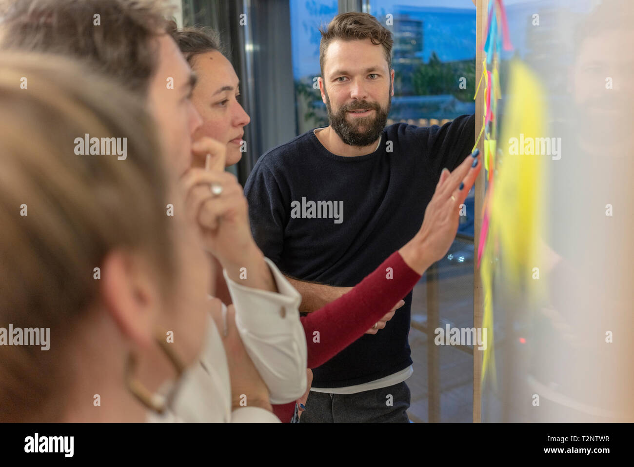 Mid adult business team looking at sticky notes on office whiteboard Stock Photo