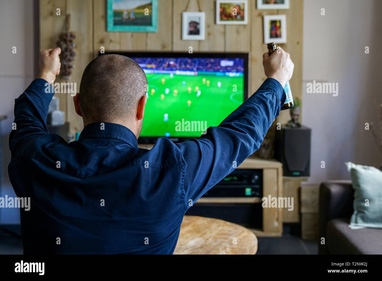 watching an important soccer match at home. Man on the couch is cheering for his favorite team Stock Photo