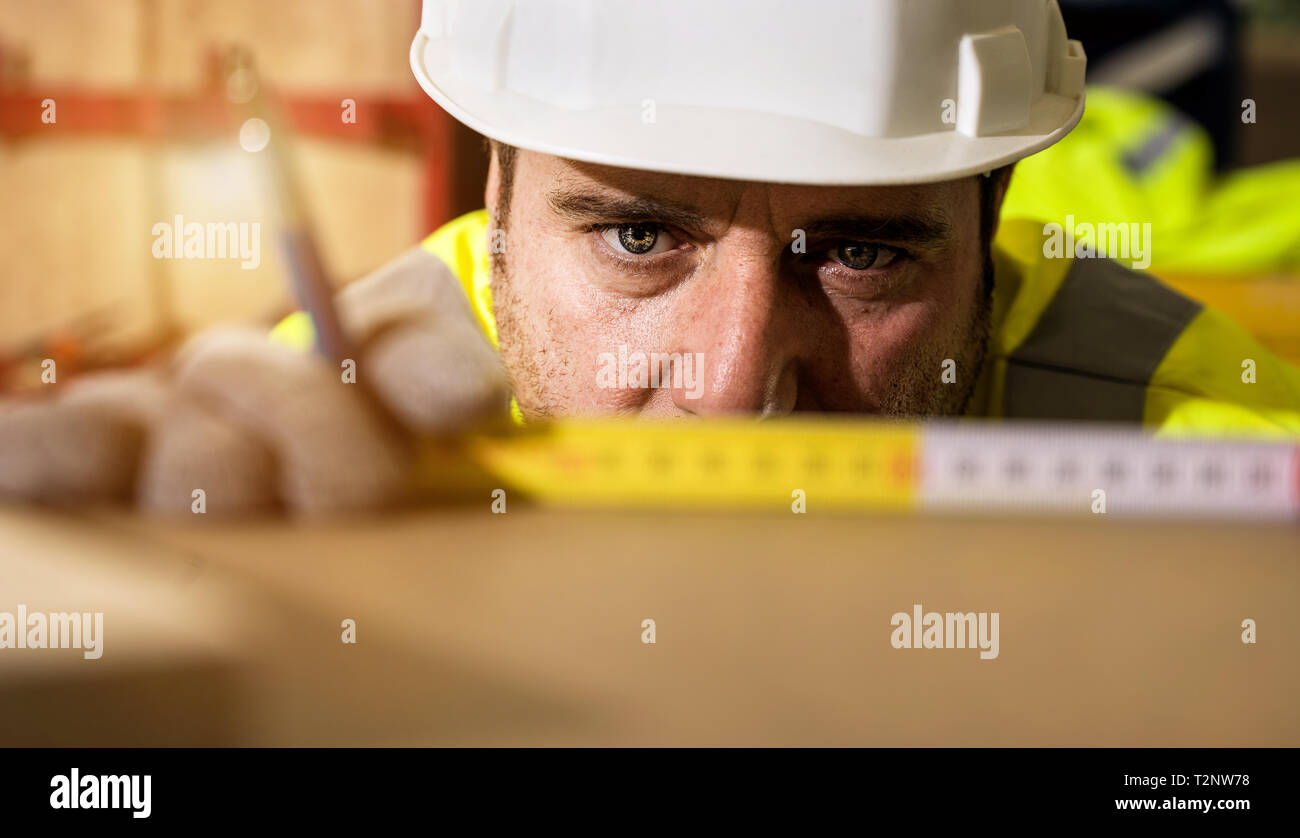 Workman in hard hat measuring surface, close up Stock Photo