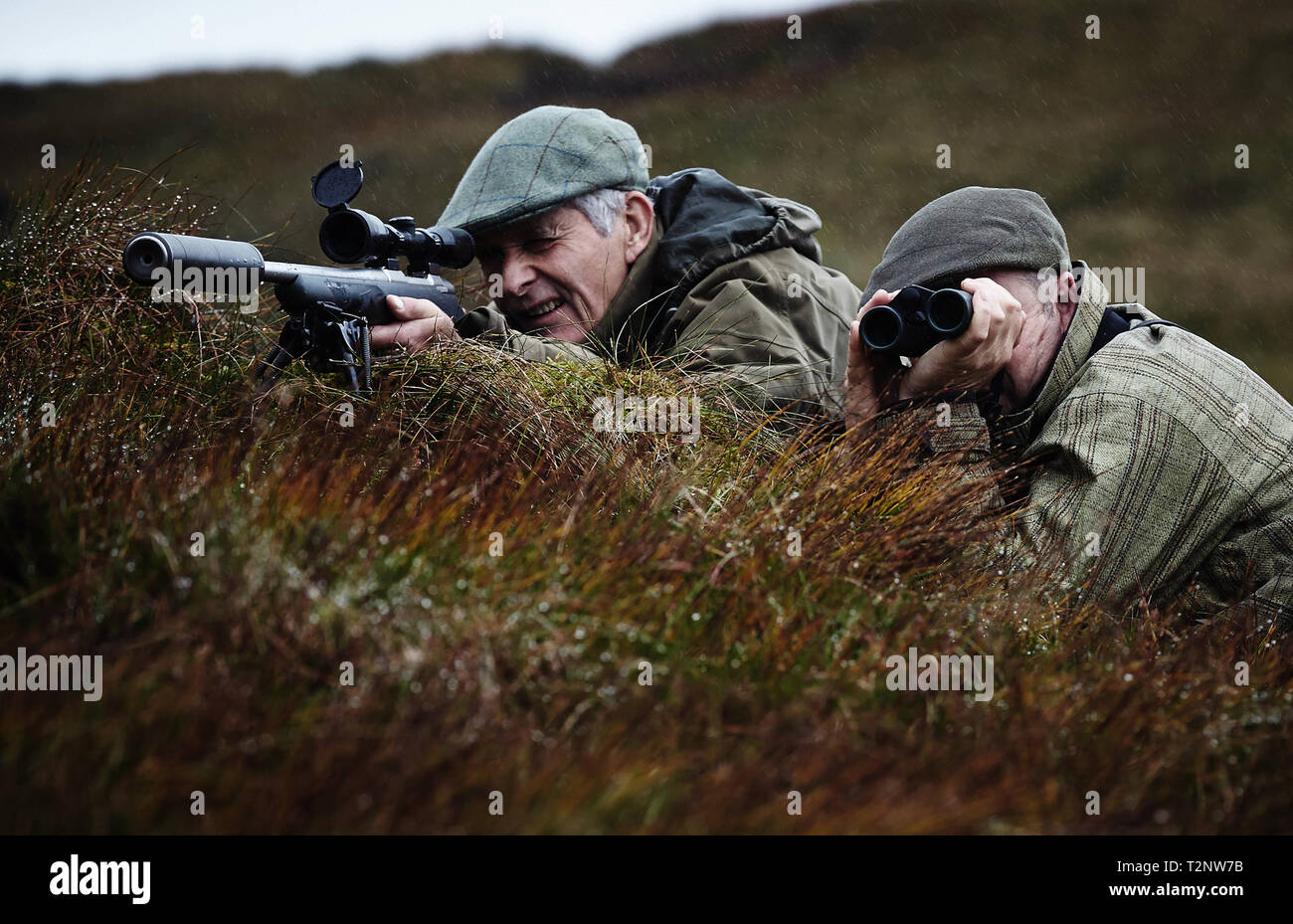 Man and gamekeeper deer stalking on moorland, Scottish Highlands Stock Photo