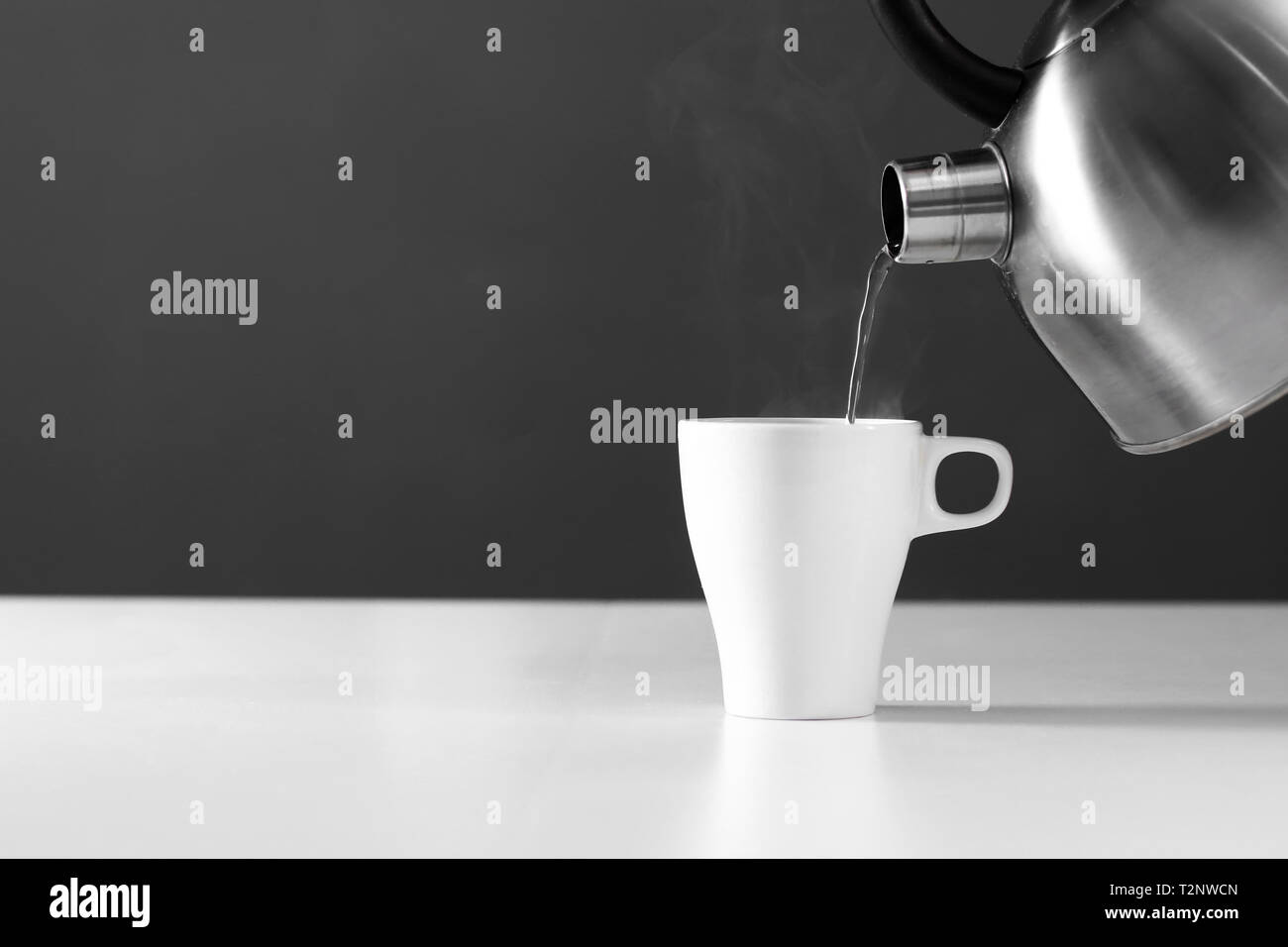 https://c8.alamy.com/comp/T2NWCN/kettle-pouring-boiling-water-into-a-cup-with-smoke-on-wood-table-T2NWCN.jpg