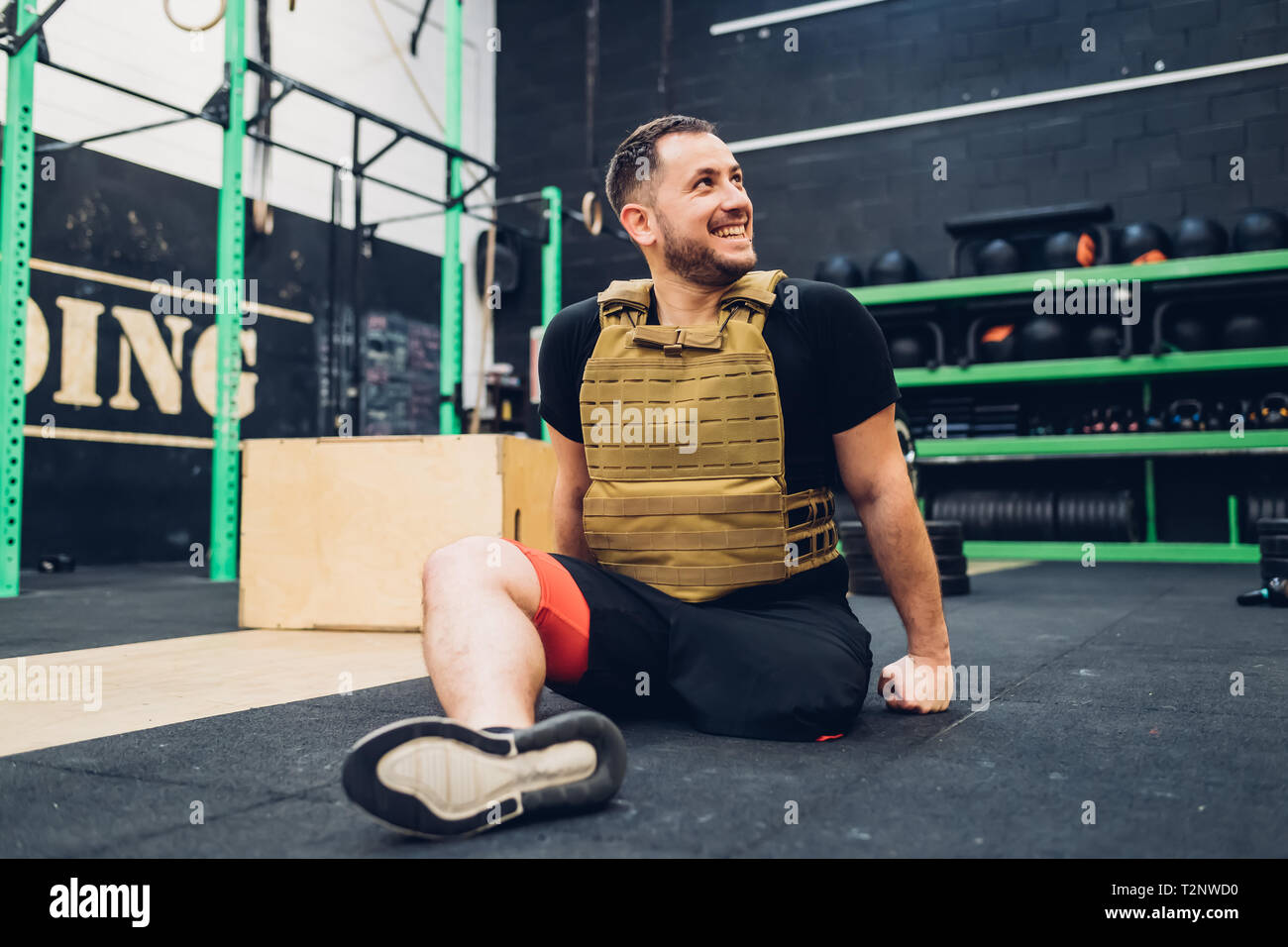 Man with disability sitting on gym floor smiling Stock Photo