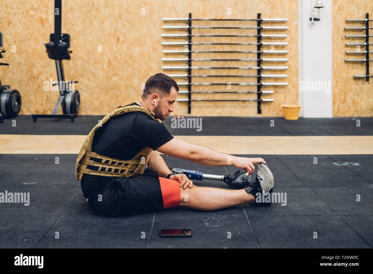 Man with prosthetic leg stretching on gym floor Stock Photo