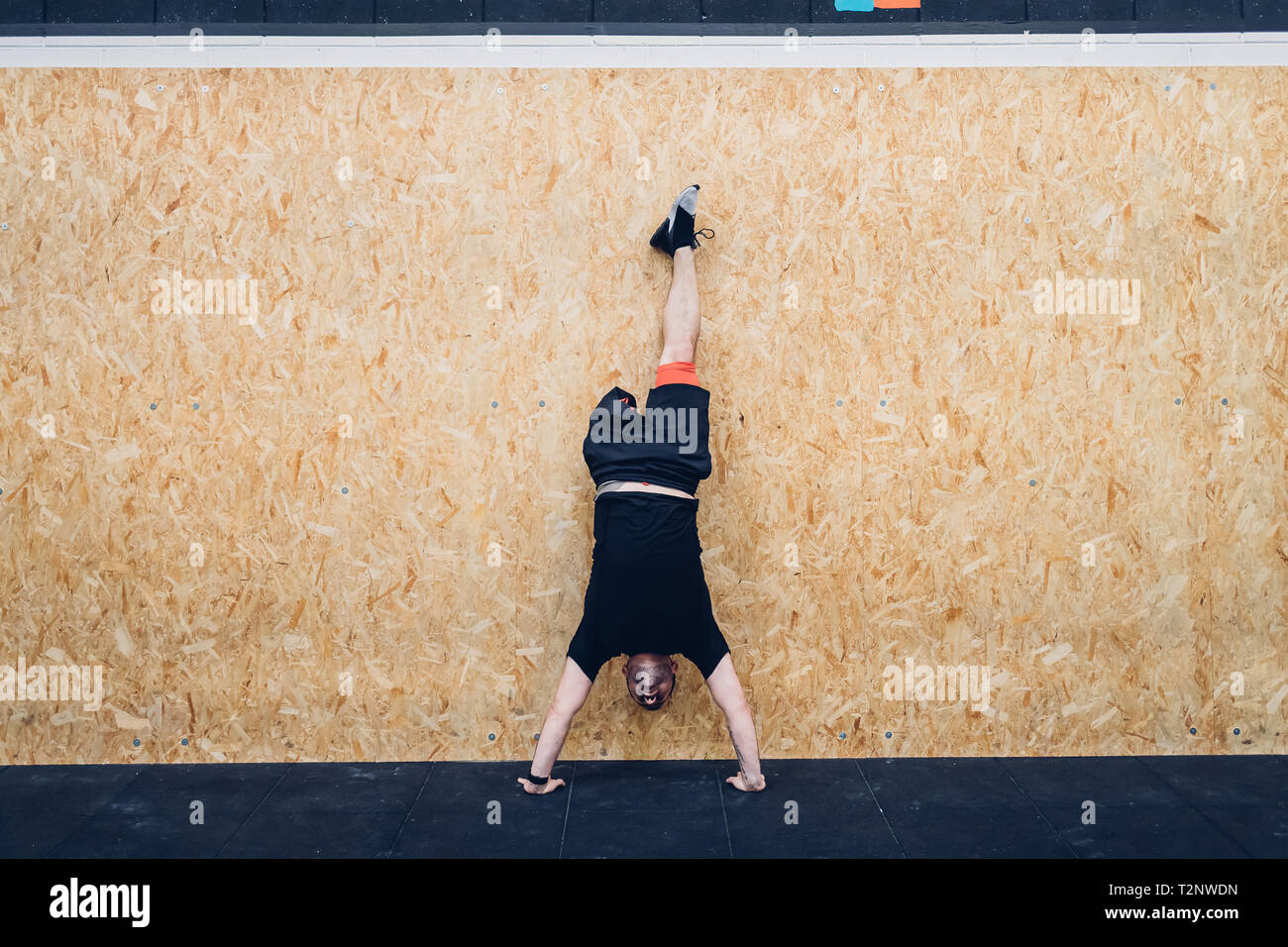 Man with disability doing handstand against chipboard wall Stock Photo