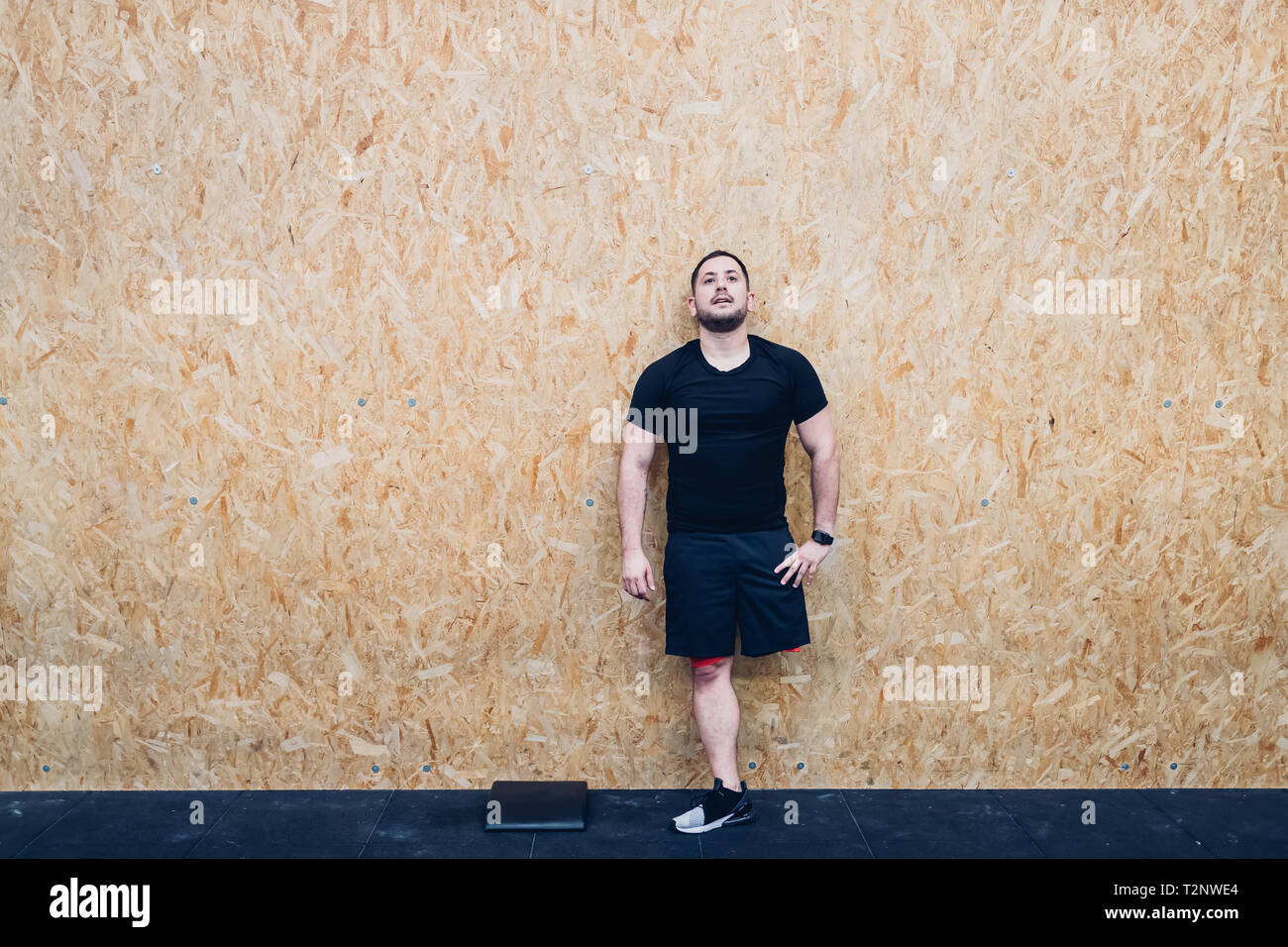 Man with disability leaning against chipboard wall Stock Photo