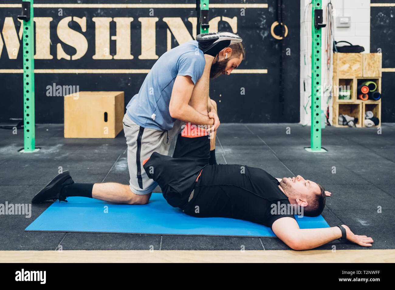 Personal trainer working with man with disability in gym Stock Photo