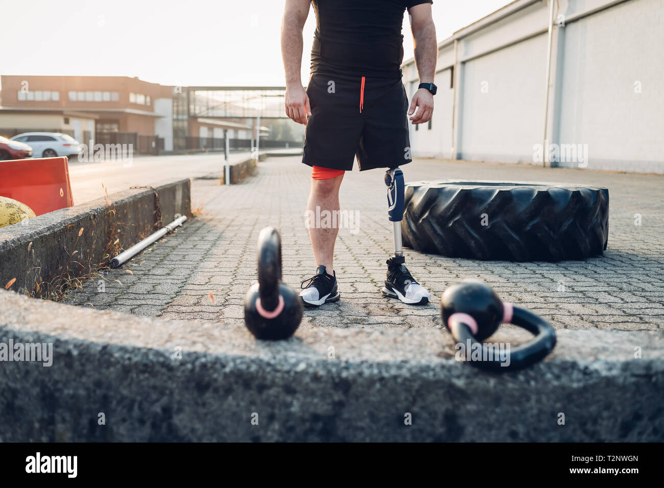 Man with prosthetic leg beside training tyre and kettlebells Stock Photo