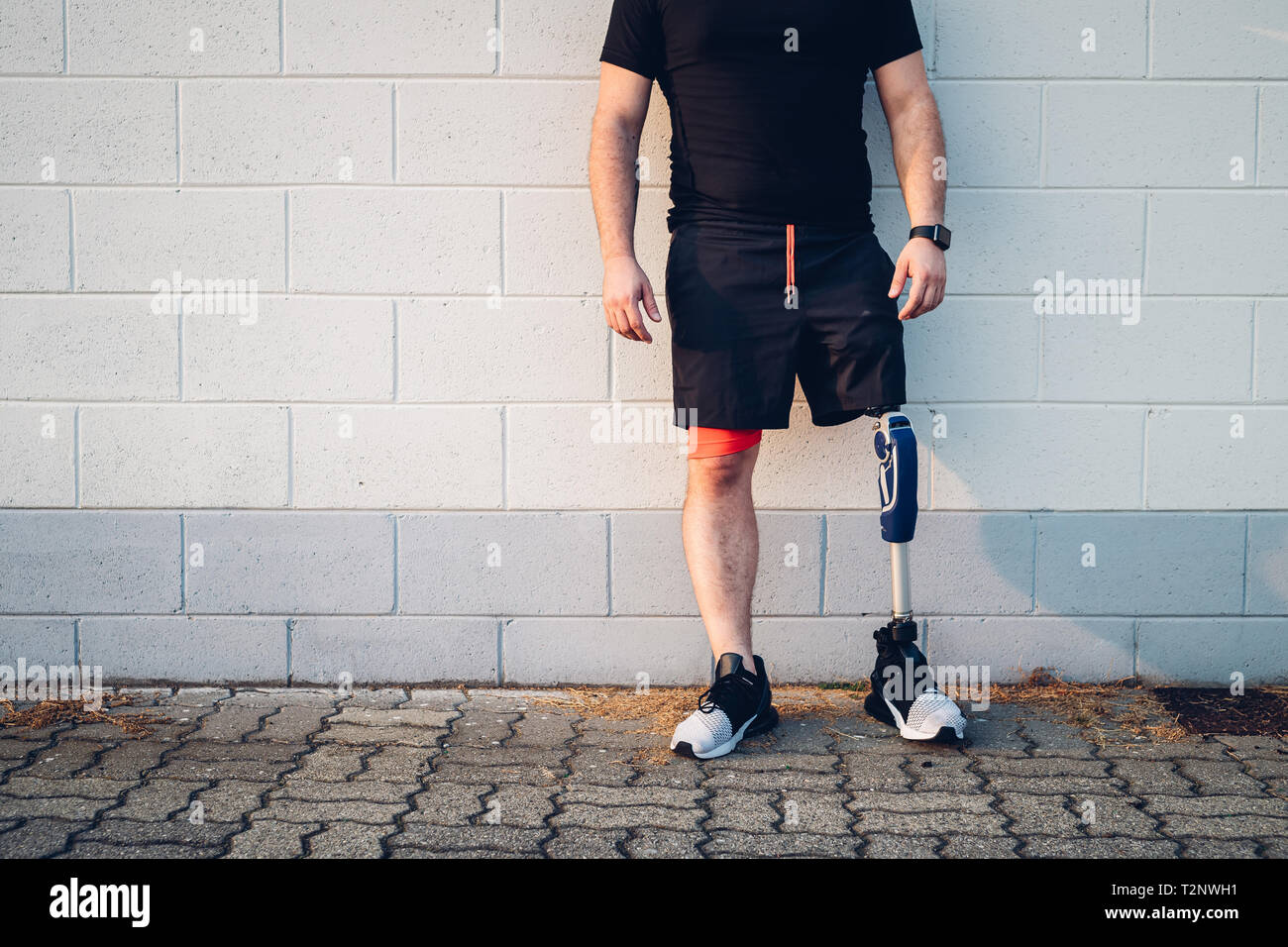 Man with prosthetic leg leaning on wall Stock Photo