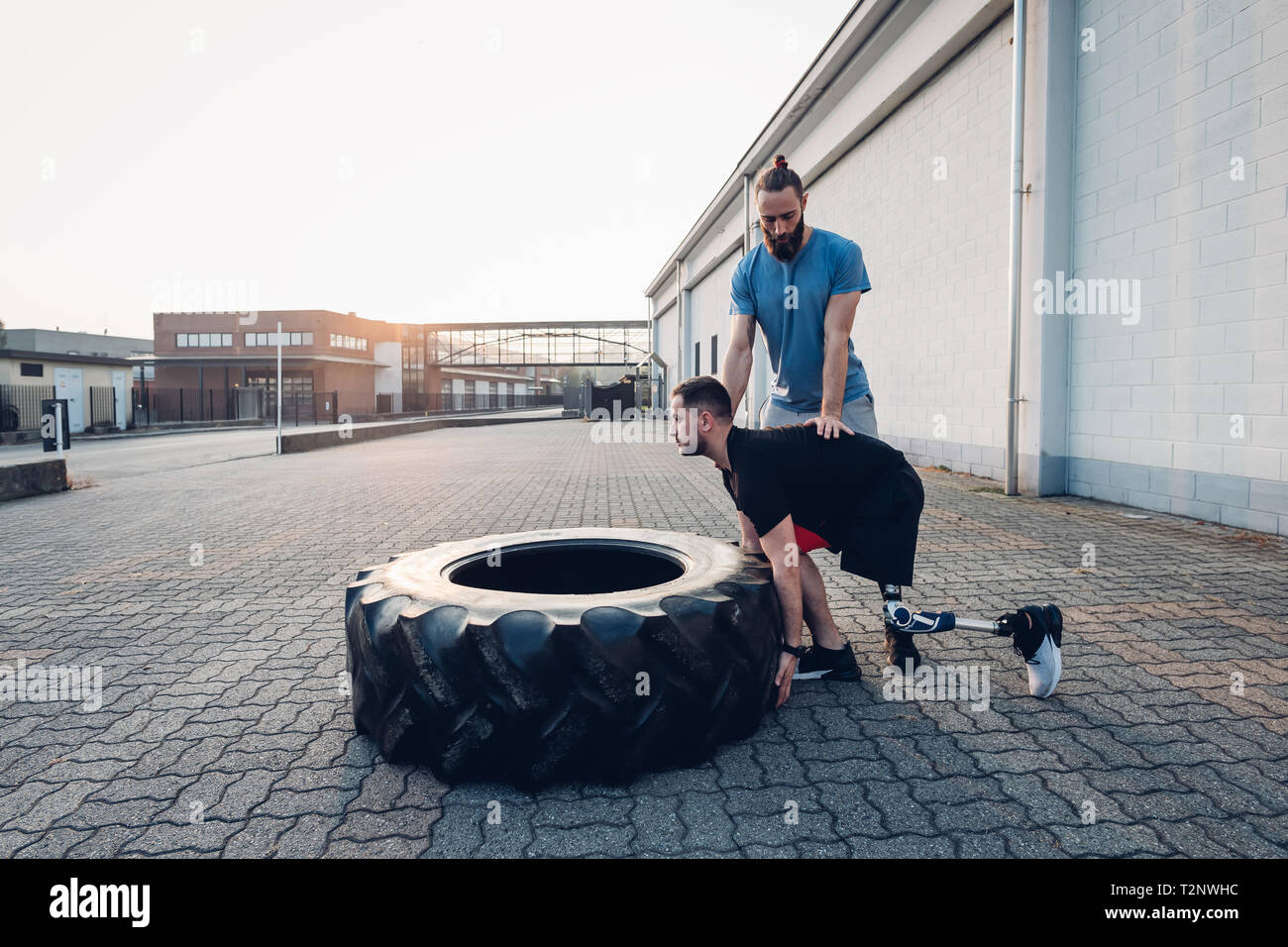 Man with prosthetic leg weight training with giant tyre Stock Photo