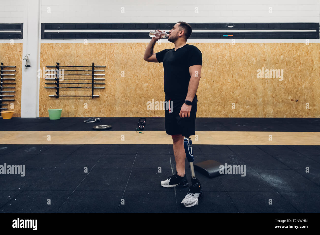 Man with prosthetic leg drinking water in gym Stock Photo