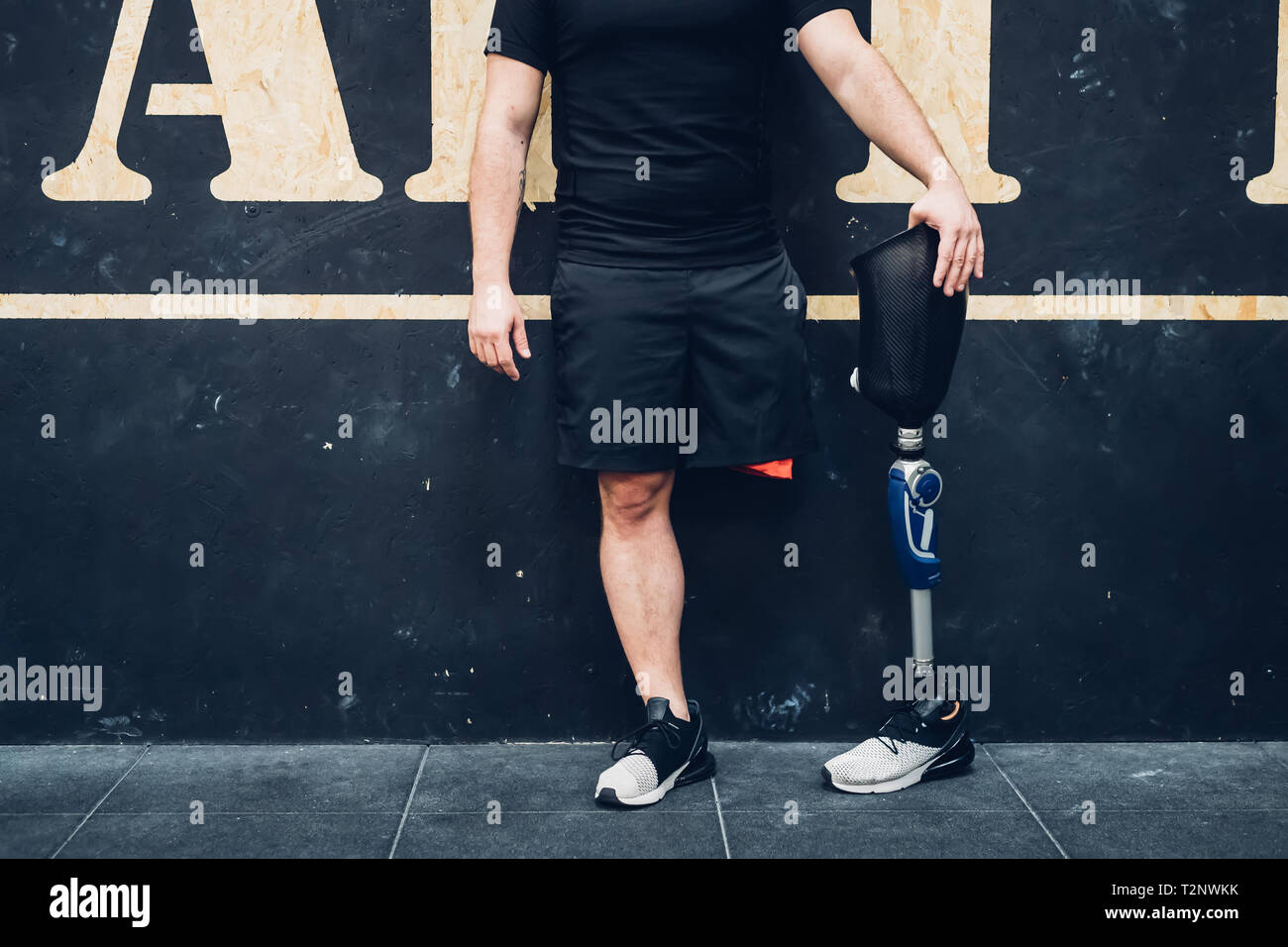 Man with prosthetic leg leaning on wall in gym Stock Photo