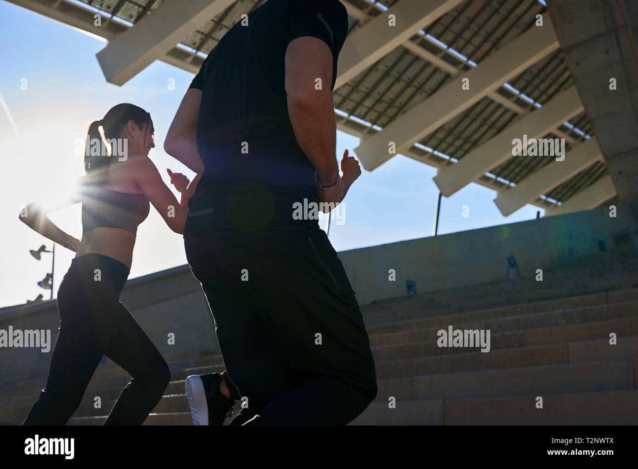 Friends jogging up steps in sports stadium Stock Photo