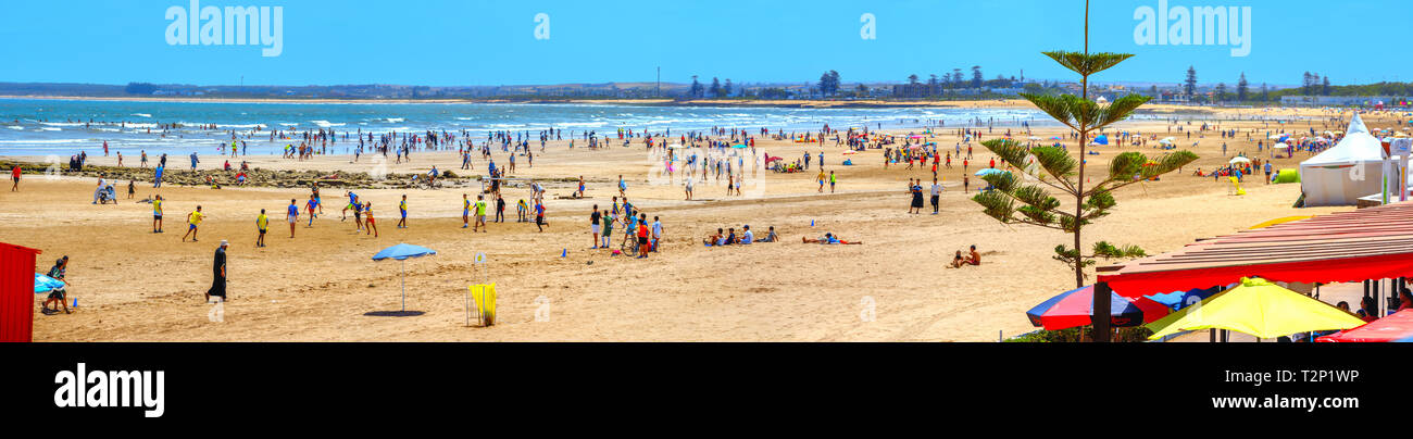 Panoramic view of seashore with wide beaches and people having fun playng  football in sunny day. Essaouira, Morocco, North Africa Stock Photo