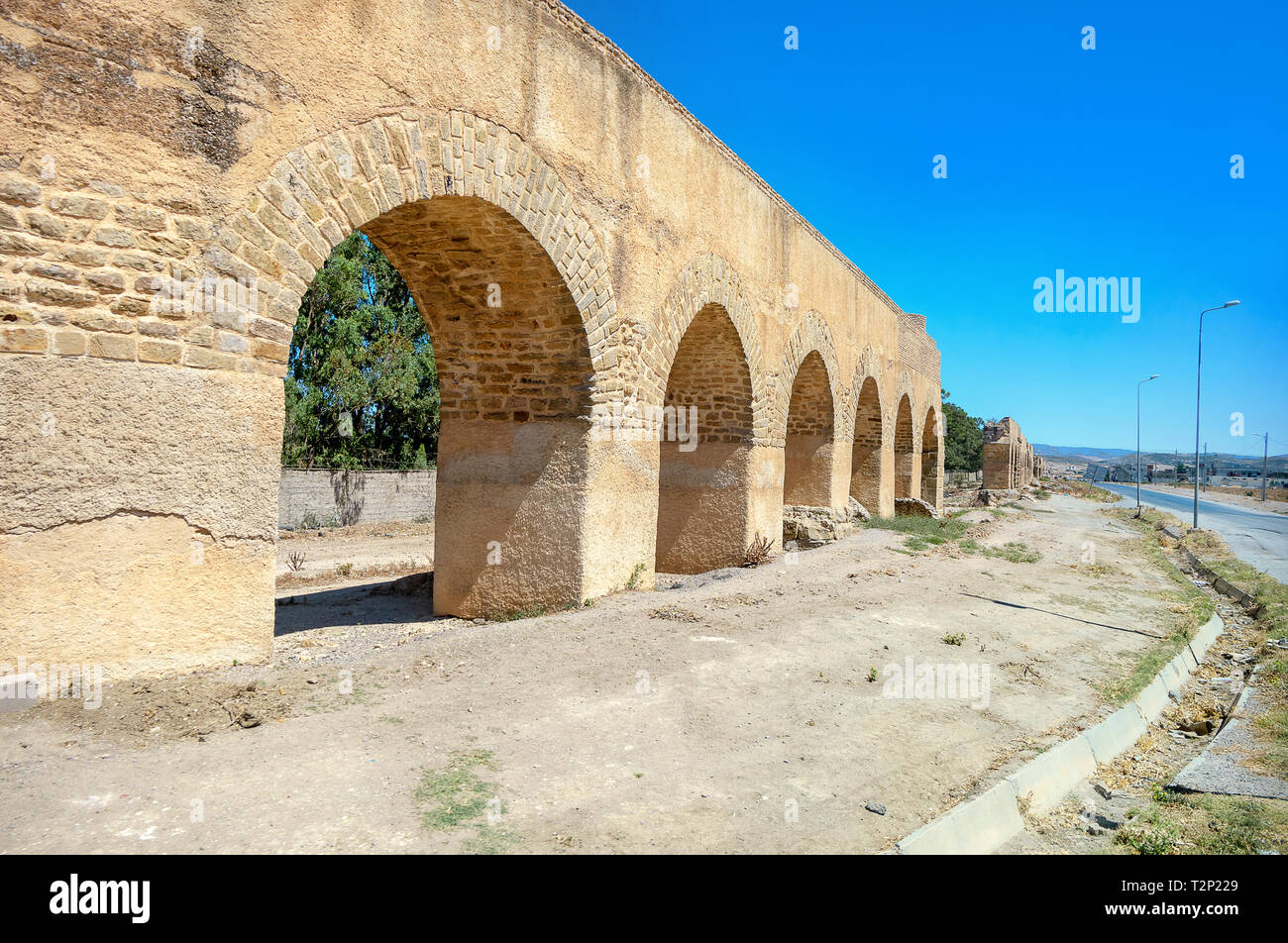 Ruins of ancient aqueduct along road near roman town Uthina (Oudhna). Tunisia, North Africa Stock Photo