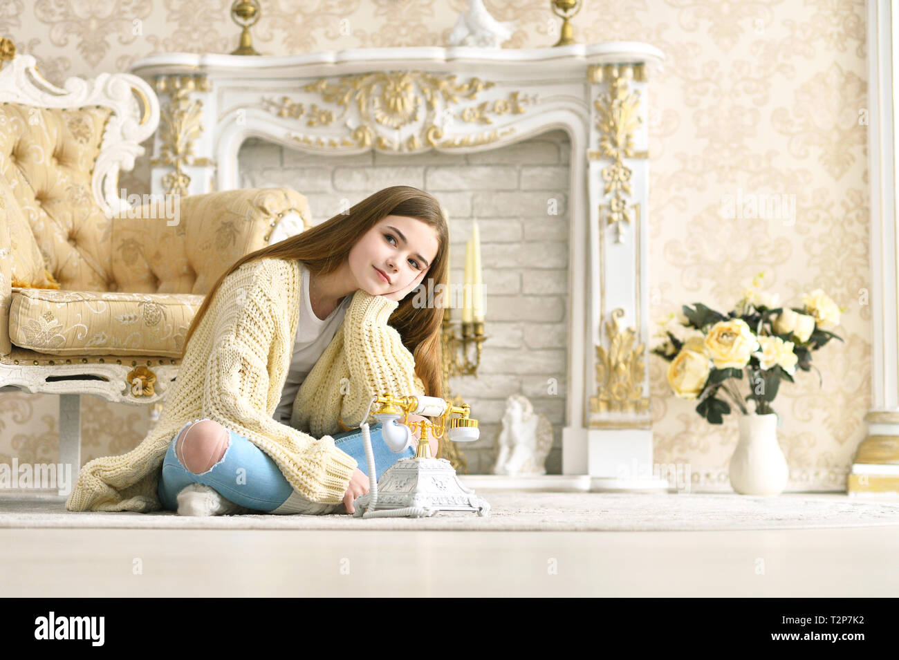 Portrait of beautiful teen girl sitting on floor near vintage phone ...