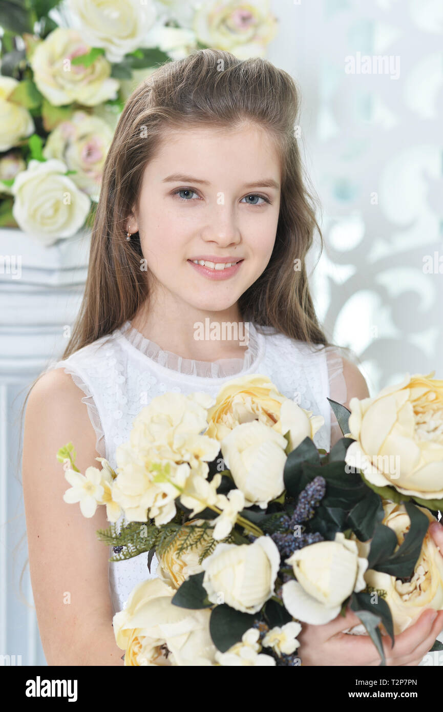 Happy little girl in white dress posing with flowers Stock Photo - Alamy