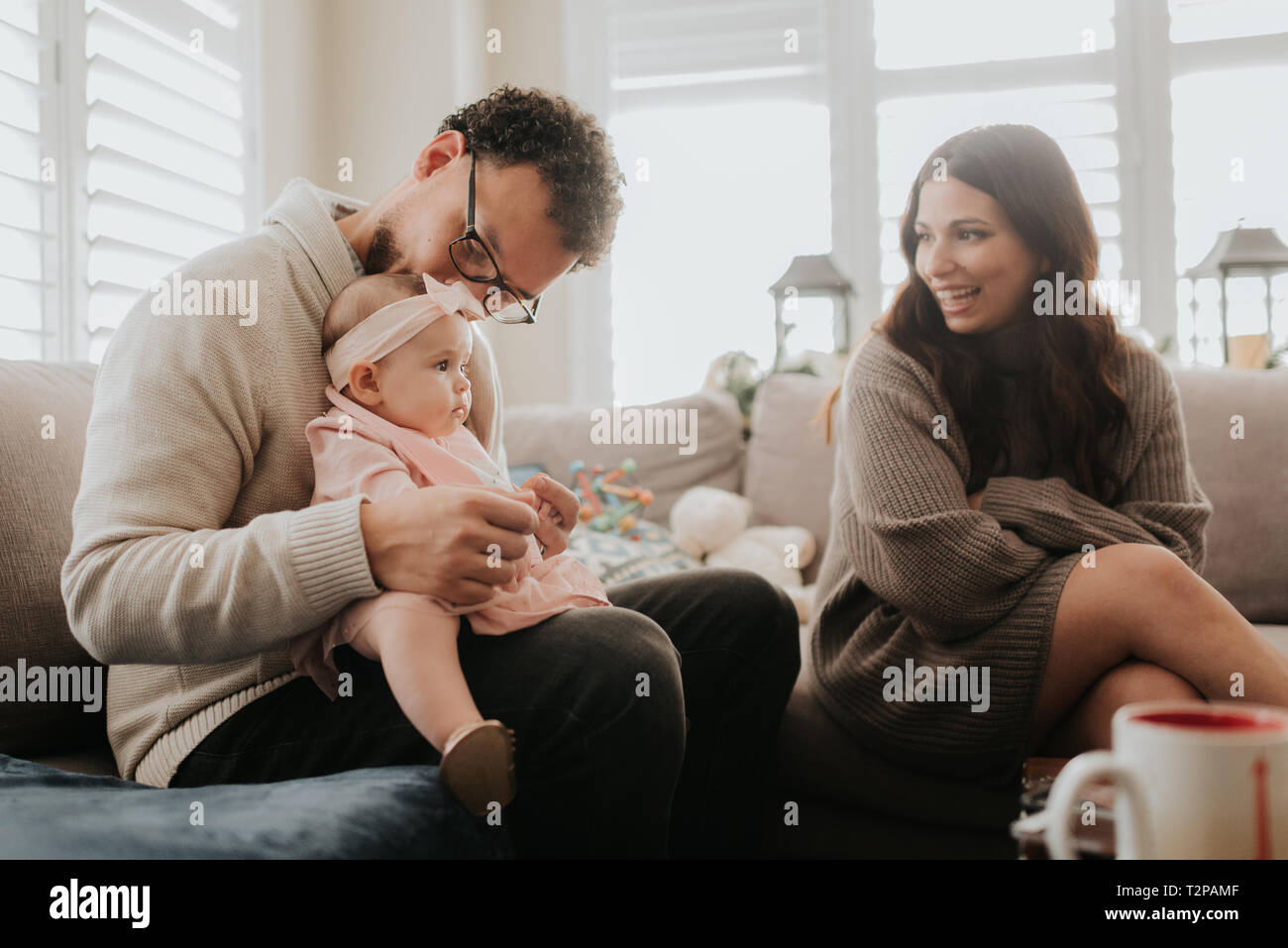 Couple playing with baby daughter on sofa Stock Photo