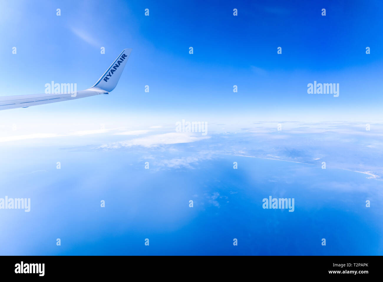 Valencia, Spain - March 8, 2019: Flaps of an Ryanair airplane seen from inside during a flight over the clouds of the sky. Stock Photo