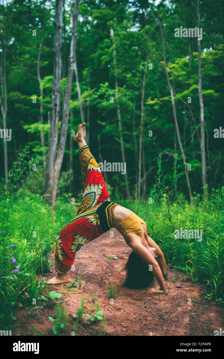 Woman doing backbend pose in forest Stock Photo