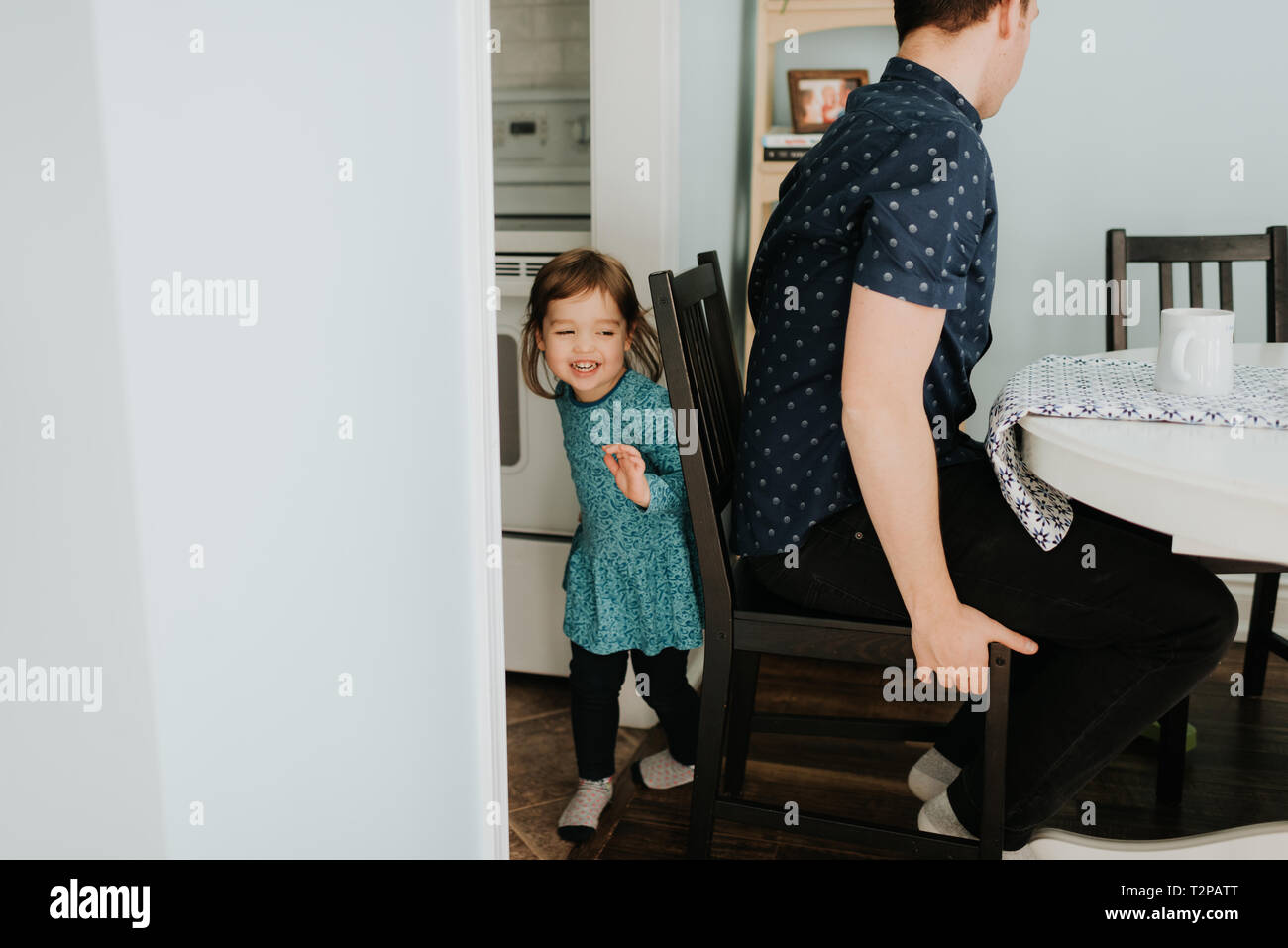Female toddler hiding from father at table Stock Photo