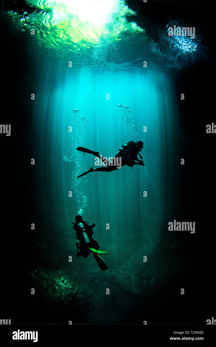 Underwater view of male and female scuba divers exploring cenote called the pit, Tulum, Quintana Roo, Mexico Stock Photo