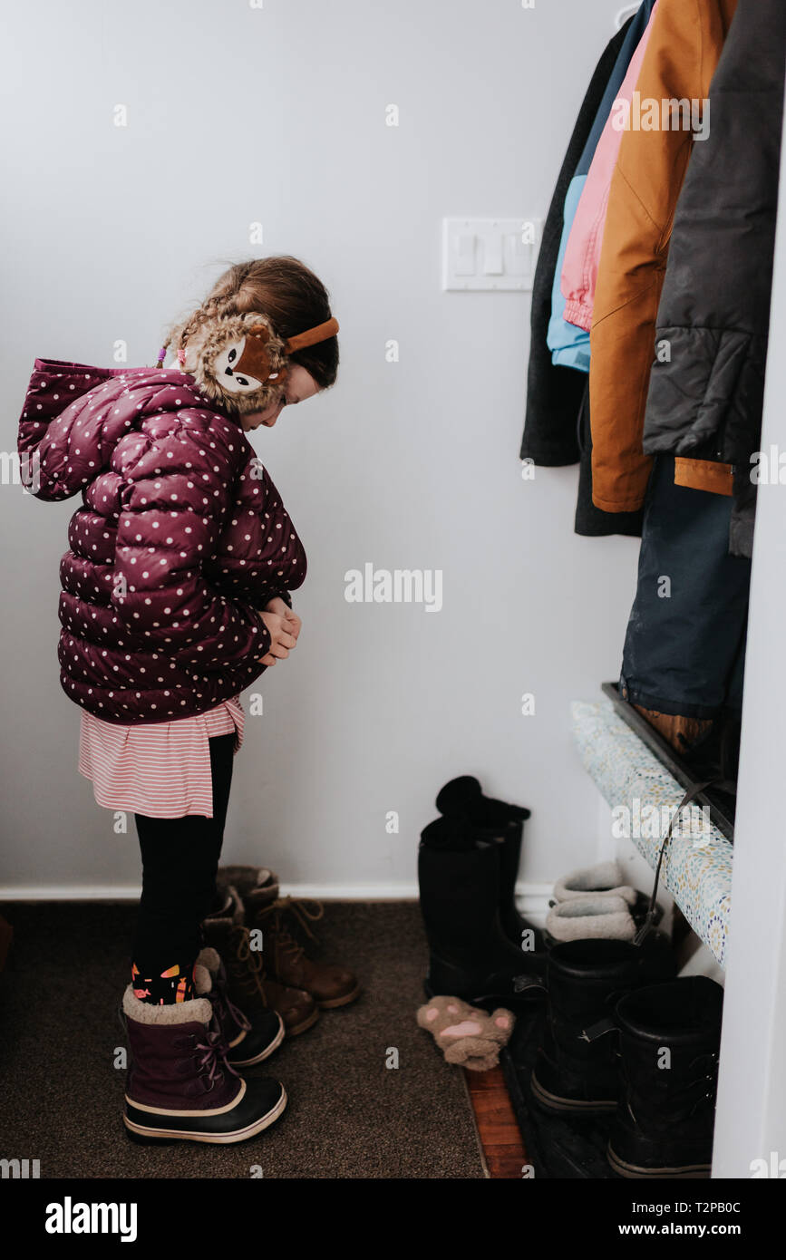 Girl putting on jacket in cloakroom Stock Photo - Alamy