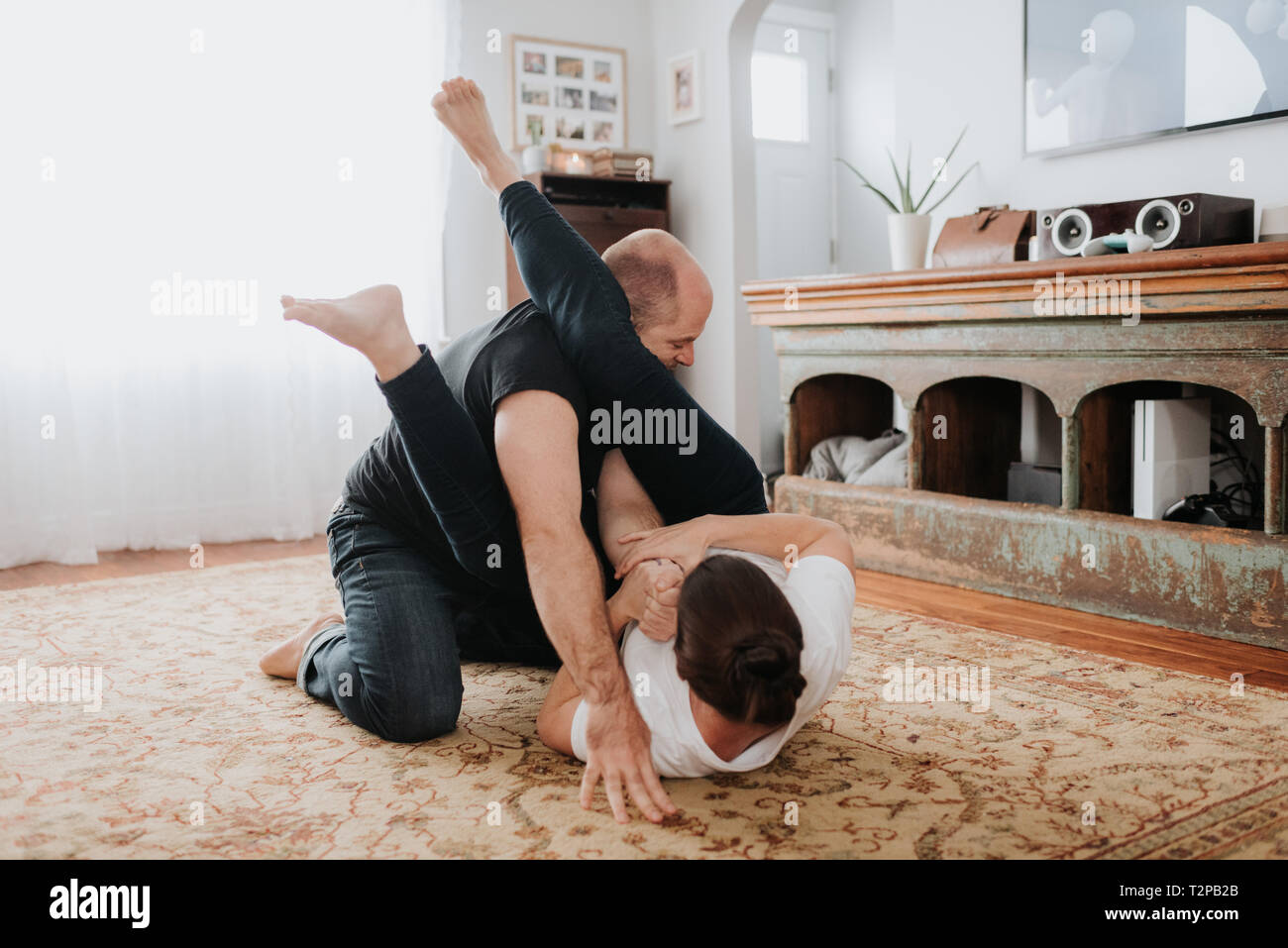 Couple wrestling on carpet at home Stock Photo