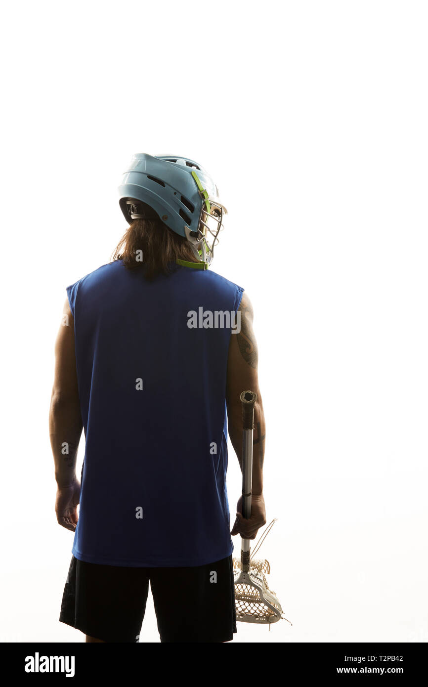 Young male lacrosse player holding lacrosse stick, rear view against