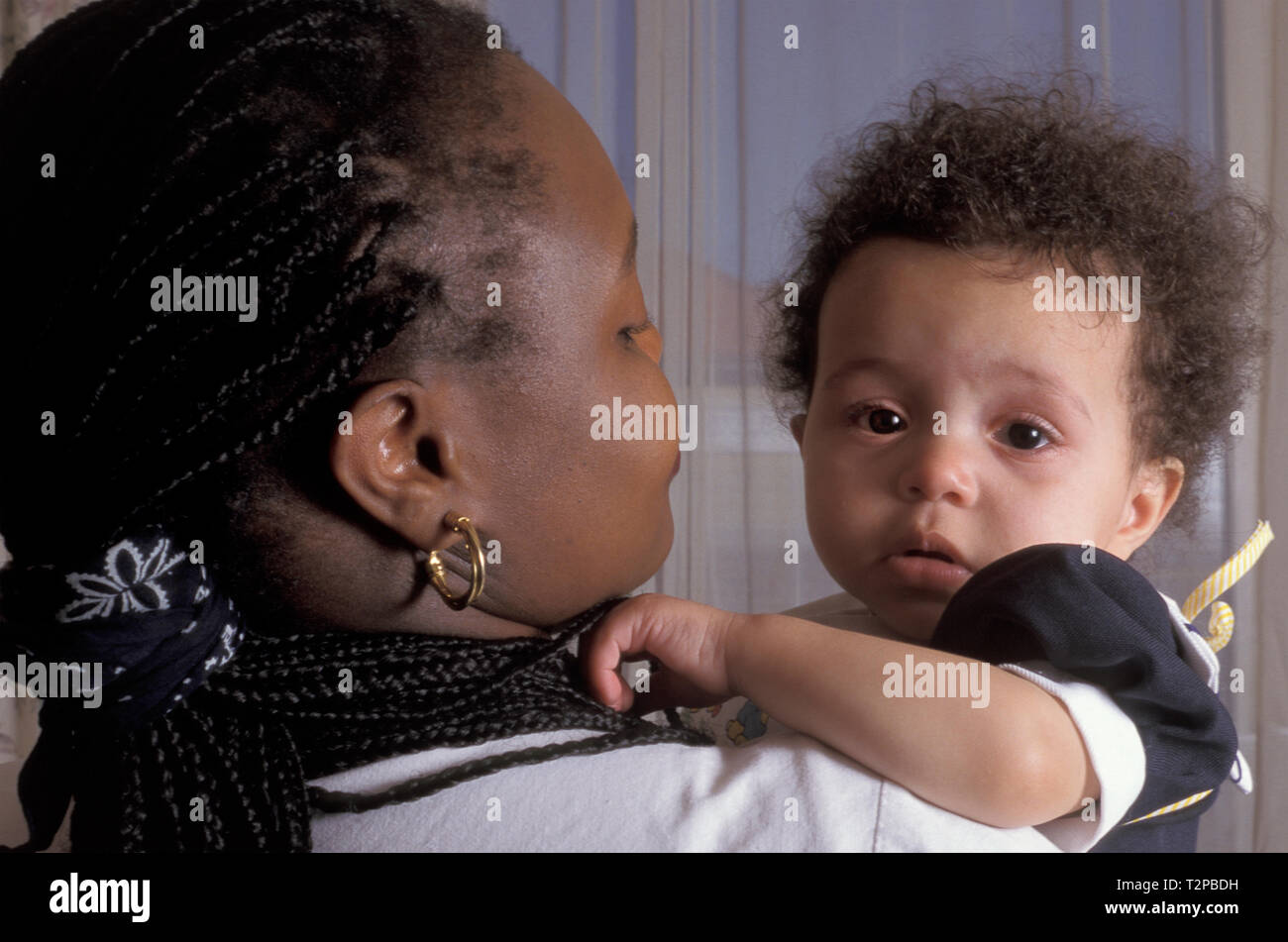 black mother holding her crying toddler Stock Photo
