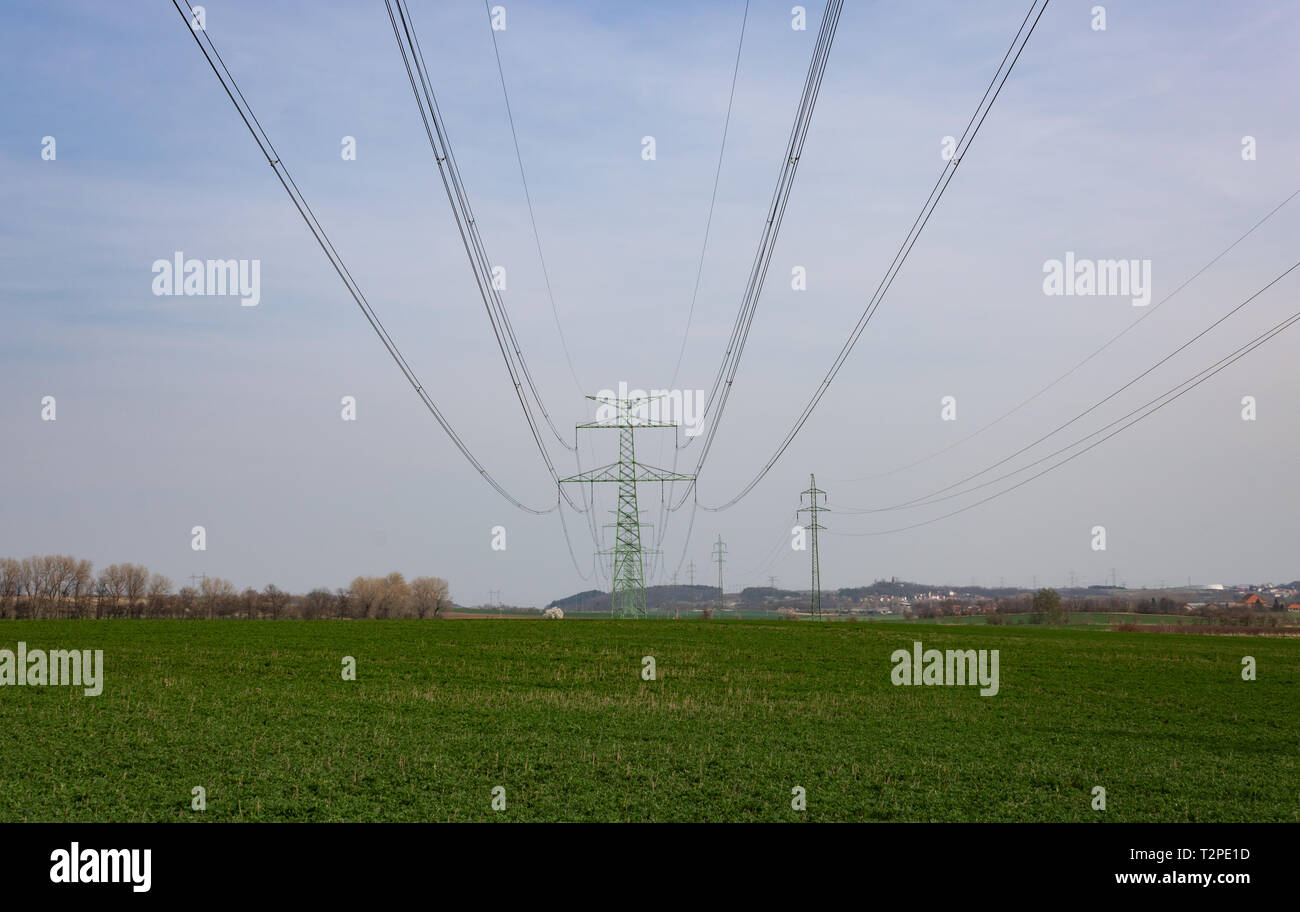 Electric high voltage pylon for power distribution line standing on green field Stock Photo