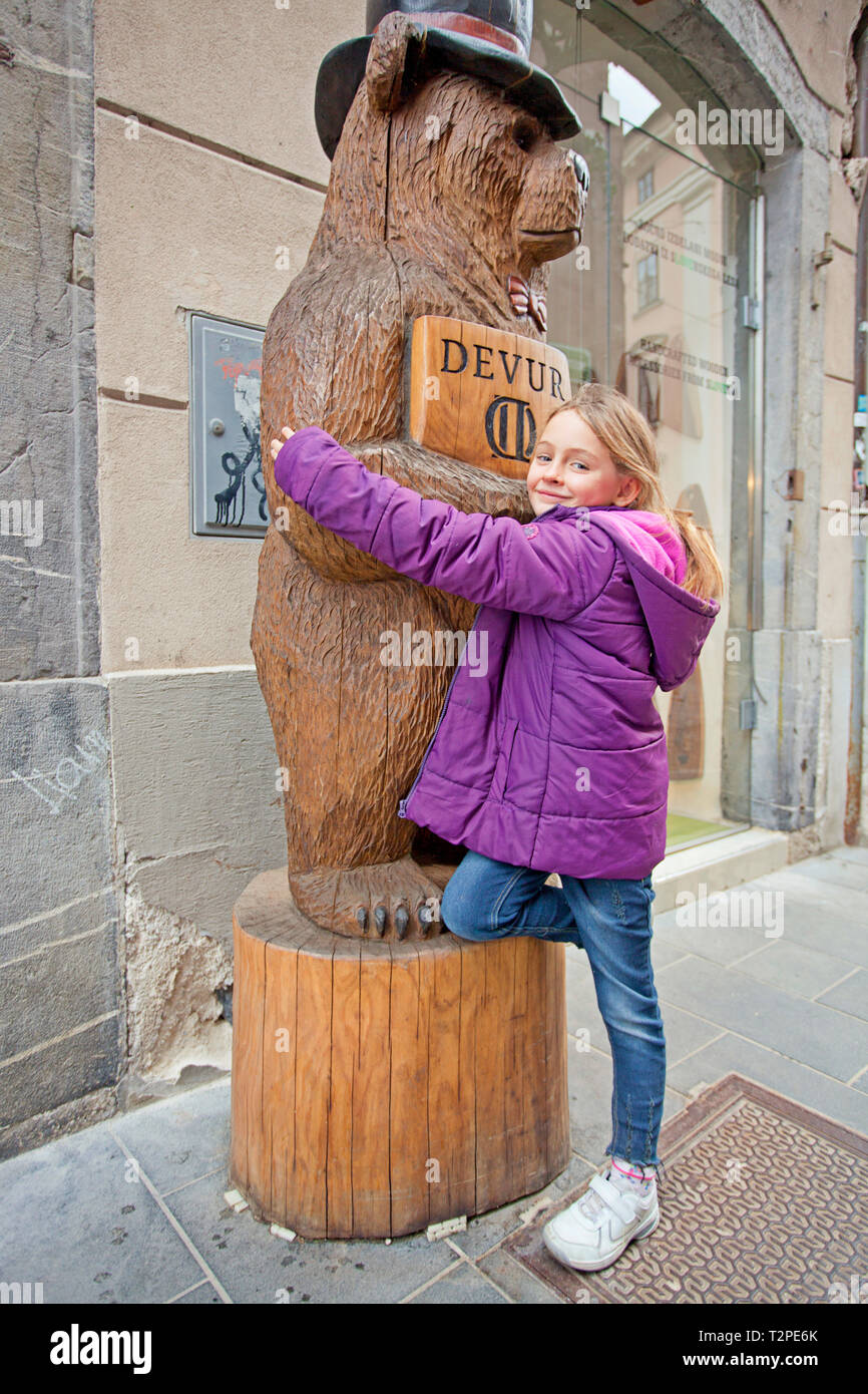 Pretty girl hugging a wooden bear Stock Photo - Alamy