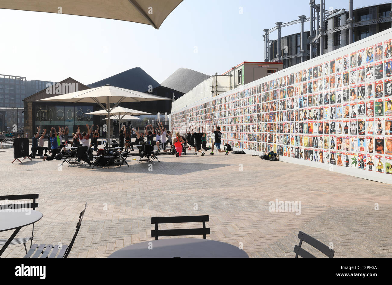 Fitness group in front of exhibition of Face magazine covers on side of Lewis Cubitt Square at CDY, Kings Cross, London, UK Stock Photo
