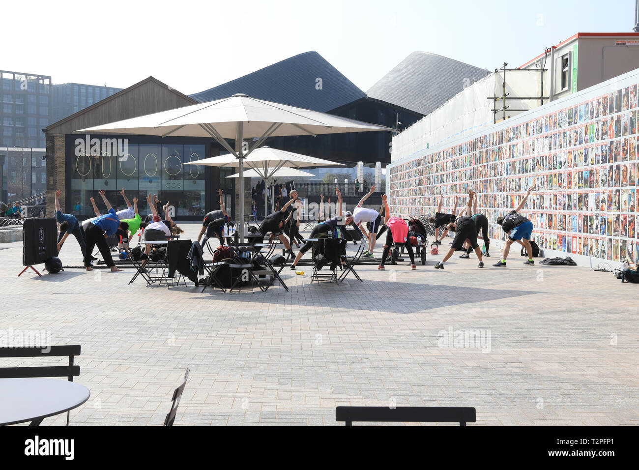 Fitness group in front of exhibition of Face magazine covers on side of Lewis Cubitt Square at CDY, Kings Cross, London, UK Stock Photo
