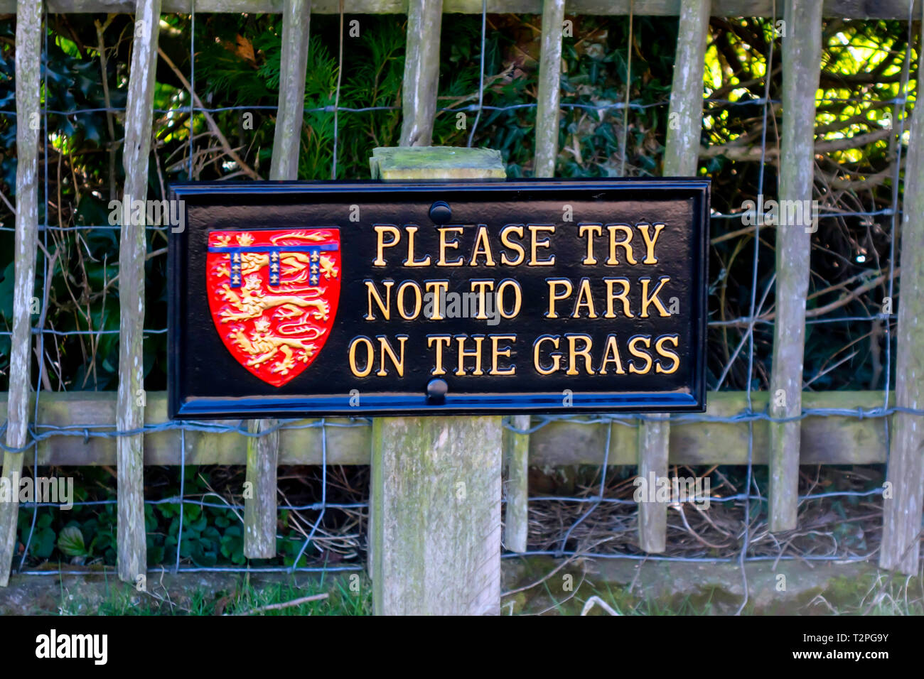 Parking Sign Please Try Not To Park on the Grass black with gold lettering and the crest of the Duchy of Lancaster in Goathland North Yorkshire Stock Photo