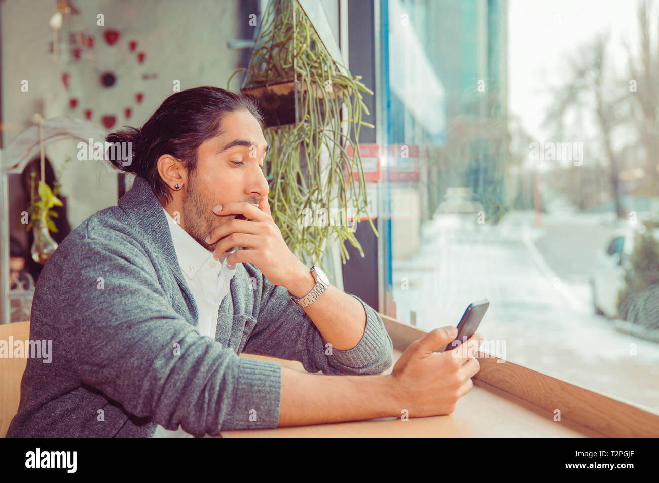sleepy funny man, hand on mouth yawning looking at smart phone being bored by phone conversation, texting. Closeup portrait of a guy wearing casual we Stock Photo
