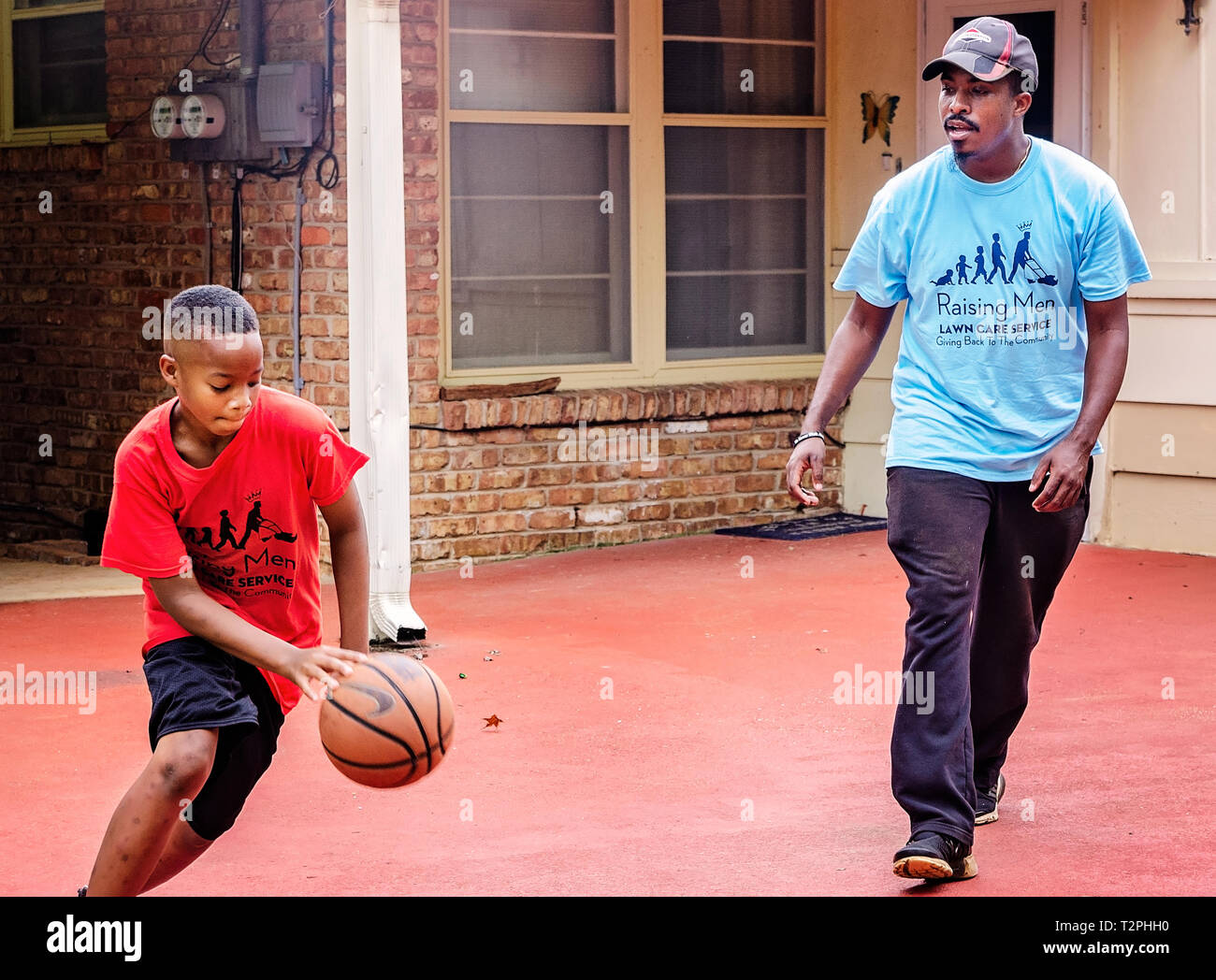 Quay Knight dribbles a basketball as Rodney Smith Jr. offers suggestions on his technique, Aug. 1, 2018, in Huntsville, Alabama. Stock Photo