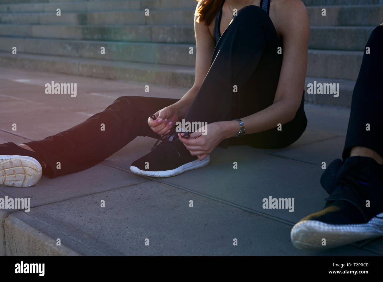 Woman tying shoelace on steps in sports stadium Stock Photo