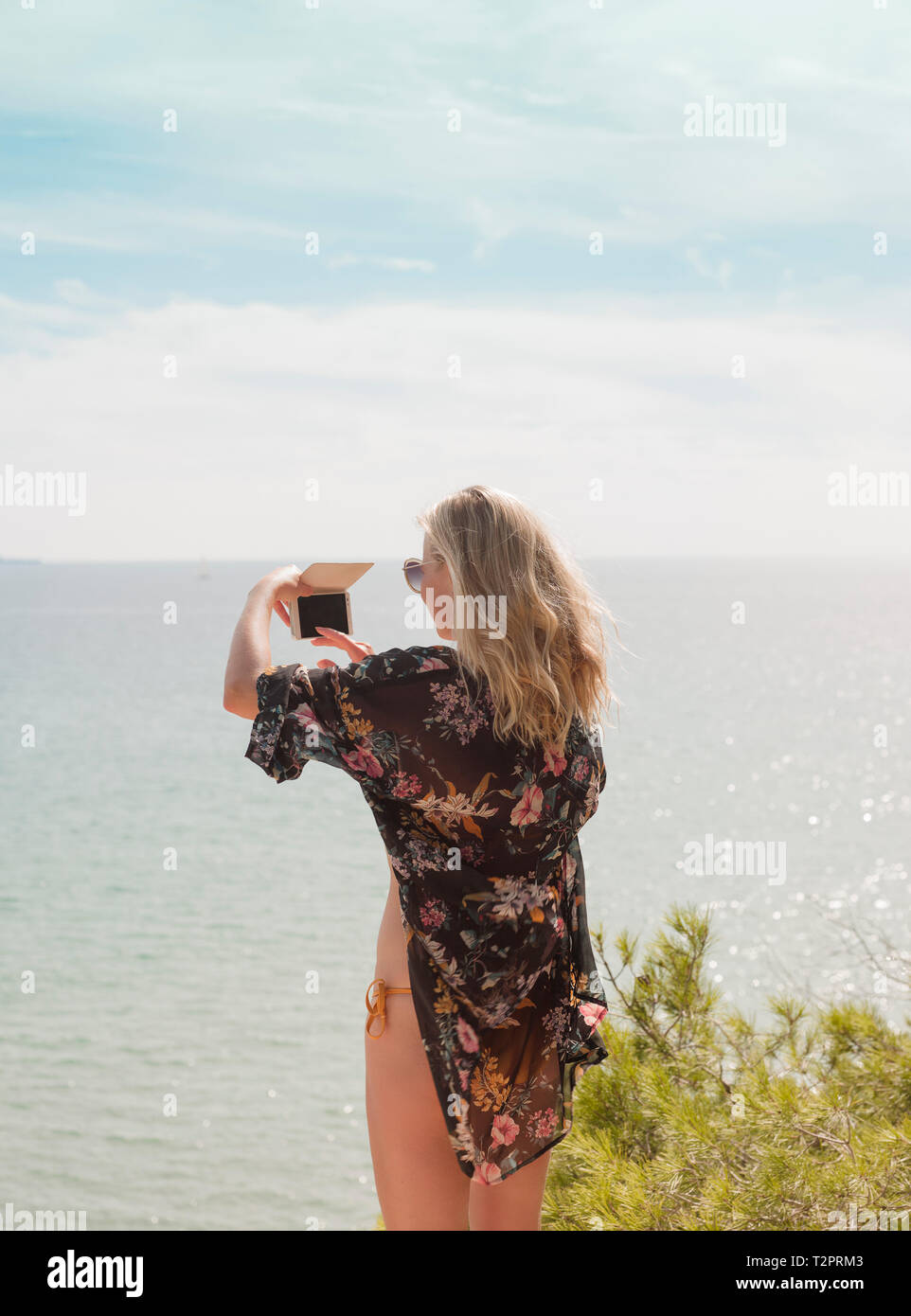 Woman taking photograph of sea on sunny day Stock Photo